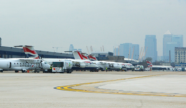 Aviones en la plataforma del aeropuerto. Al fondo, alguno de los rascacielos de la City